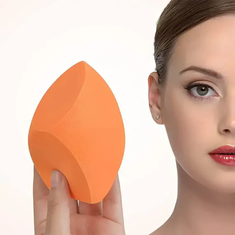 Person holding an orange makeup sponge next to their face, showcasing its texture and shape.